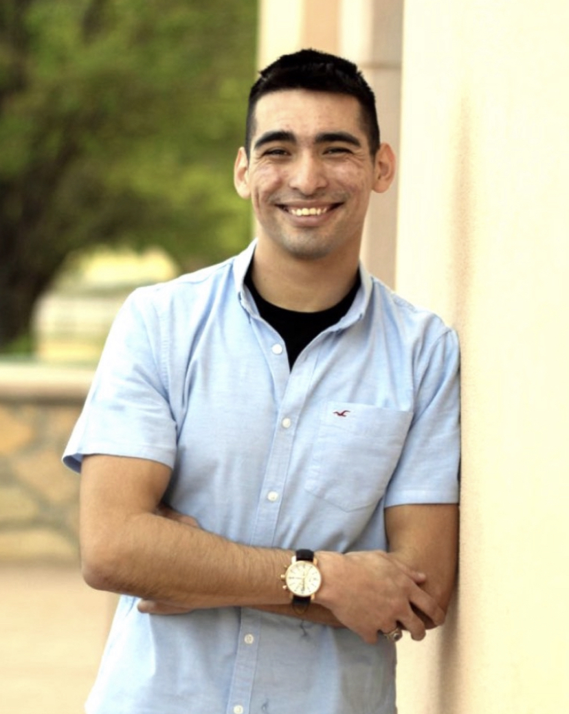 Waist up photo of Carol Avila leaning against a wall with a light blue collared shirt